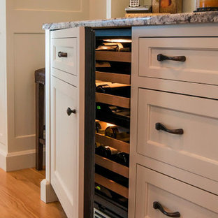 Eat-in kitchen - large traditional u-shaped light wood floor and brown floor eat-in kitchen idea in Boston with an undermount sink, beaded inset cabinets, white cabinets, granite countertops, beige backsplash, stainless steel appliances, an island and stone tile backsplash