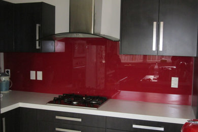 ウェリントンにあるモダンスタイルのおしゃれなキッチン (赤いキッチンパネル、ガラス板のキッチンパネル) の写真