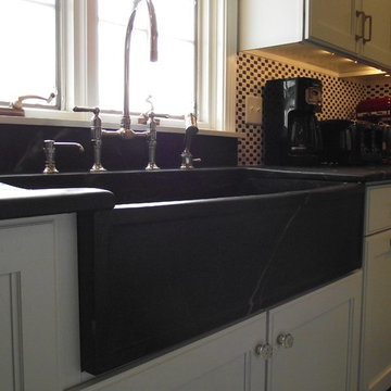 Custom soapstone farmhouse sink, bridge faucet, black and white mosaic backsplas