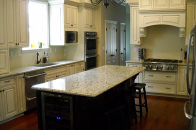 Klassisk inredning av ett avskilt, mellanstort u-kök, med en undermonterad diskho, luckor med upphöjd panel, vita skåp, granitbänkskiva, beige stänkskydd, rostfria vitvaror, mörkt trägolv och en köksö