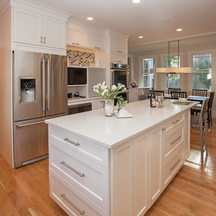 Immagine di una cucina chic di medie dimensioni con lavello stile country, ante con bugna sagomata, ante bianche, top in quarzo composito, paraspruzzi grigio, paraspruzzi con piastrelle di vetro, elettrodomestici in acciaio inossidabile e pavimento in legno massello medio