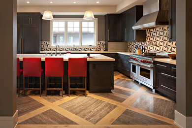Large classic l-shaped kitchen in Calgary with multi-coloured splashback, medium hardwood flooring, an island, a submerged sink, recessed-panel cabinets, dark wood cabinets and stainless steel appliances.