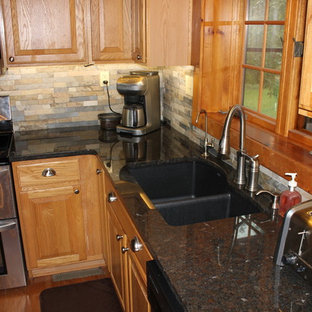 Mid-sized country l-shaped eat-in kitchen in Kansas City with an undermount sink, raised-panel cabinets, light wood cabinets, granite benchtops, grey splashback, slate splashback, stainless steel appliances, light hardwood floors and with island.