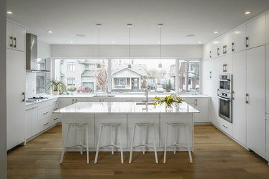 Example of a mid-sized trendy u-shaped medium tone wood floor and brown floor kitchen design in Vancouver with a single-bowl sink, flat-panel cabinets, white cabinets, solid surface countertops, white backsplash, subway tile backsplash, stainless steel appliances and an island