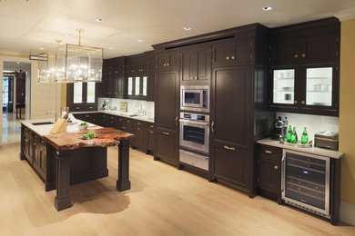Example of a transitional single-wall light wood floor eat-in kitchen design in New York with flat-panel cabinets, dark wood cabinets, marble countertops, white backsplash, stainless steel appliances and two islands