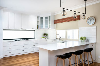 Ejemplo de cocina contemporánea con encimera de mármol, salpicadero blanco, salpicadero de azulejos tipo metro y suelo de madera clara