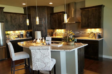 Example of a mid-sized transitional l-shaped dark wood floor and brown floor kitchen design in Denver with a double-bowl sink, shaker cabinets, dark wood cabinets, granite countertops, multicolored backsplash, matchstick tile backsplash, stainless steel appliances and an island