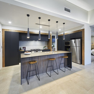 This is an example of a contemporary single-wall kitchen in Perth with an undermount sink, flat-panel cabinets, white splashback, subway tile splashback, stainless steel appliances, with island, beige floor, black benchtop, grey cabinets and quartz benchtops.