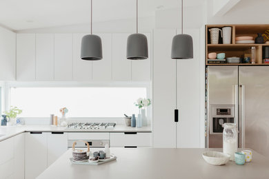 Inredning av ett nordiskt mellanstort grå grått kök, med en dubbel diskho, öppna hyllor, skåp i ljust trä, bänkskiva i betong, rostfria vitvaror, ljust trägolv och en köksö