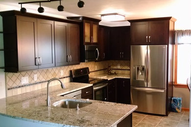 Example of a mid-sized transitional u-shaped porcelain tile eat-in kitchen design in Other with an undermount sink, shaker cabinets, dark wood cabinets, granite countertops, beige backsplash, stone tile backsplash, stainless steel appliances and a peninsula