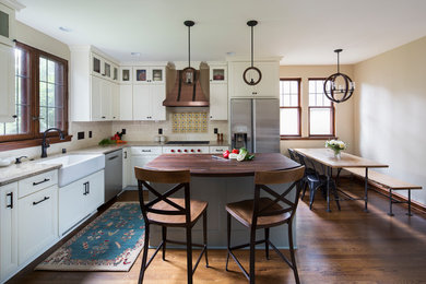Example of a mid-sized classic l-shaped dark wood floor and brown floor eat-in kitchen design in Milwaukee with a farmhouse sink, flat-panel cabinets, white cabinets, quartzite countertops, white backsplash, subway tile backsplash, stainless steel appliances, an island and multicolored countertops