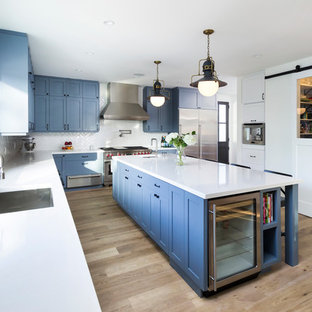 Example of a transitional l-shaped beige floor kitchen design in Los Angeles with an undermount sink, shaker cabinets, blue cabinets, white backsplash and stainless steel appliances