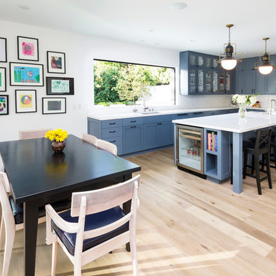 Example of a transitional l-shaped eat-in kitchen design in Los Angeles with an undermount sink, shaker cabinets, blue cabinets, white backsplash and stainless steel appliances