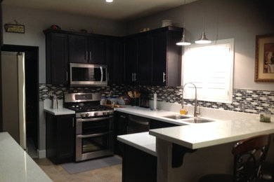 Example of a mid-sized porcelain tile kitchen design in Las Vegas with an undermount sink, brown cabinets, quartz countertops, glass sheet backsplash and stainless steel appliances