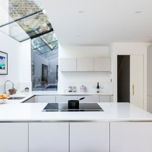 Inspiration for a contemporary u-shaped kitchen in London with a submerged sink, flat-panel cabinets, grey cabinets, a breakfast bar and white worktops.