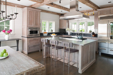 Inspiration for a large coastal l-shaped dark wood floor eat-in kitchen remodel in Bridgeport with a farmhouse sink, recessed-panel cabinets, distressed cabinets, stainless steel countertops, stainless steel appliances, gray backsplash and an island