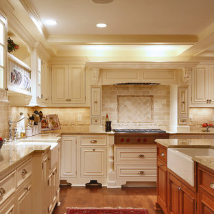 Large traditional eat-in kitchen ideas - Large elegant u-shaped medium tone wood floor eat-in kitchen photo in New York with a farmhouse sink, raised-panel cabinets, beige cabinets, granite countertops, beige backsplash, stainless steel appliances, an island and travertine backsplash