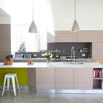 Minimalist galley kitchen photo in New York with an undermount sink, flat-panel cabinets, light wood cabinets, gray backsplash and stainless steel appliances