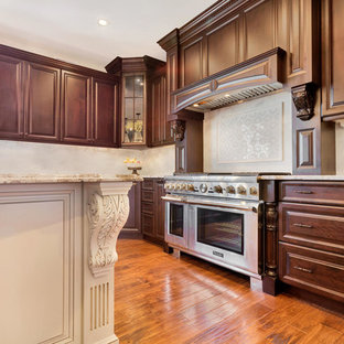 Design ideas for a large traditional u-shaped eat-in kitchen in New York with an undermount sink, raised-panel cabinets, brown cabinets, granite benchtops, white splashback, stone tile splashback, stainless steel appliances, medium hardwood floors and with island.