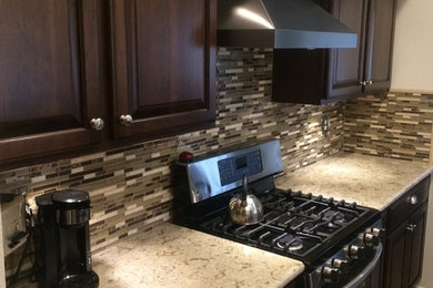 Inspiration for a mid-sized transitional l-shaped ceramic tile eat-in kitchen remodel in Los Angeles with raised-panel cabinets, dark wood cabinets, quartz countertops, multicolored backsplash, matchstick tile backsplash and stainless steel appliances
