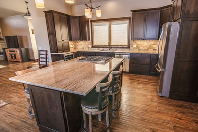 Large elegant u-shaped dark wood floor and brown floor open concept kitchen photo in Other with an undermount sink, recessed-panel cabinets, dark wood cabinets, granite countertops, beige backsplash, stone tile backsplash, stainless steel appliances, an island and beige countertops