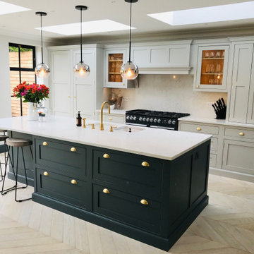Dark green kitchen island with white worktops, built-in sink and gold fittings