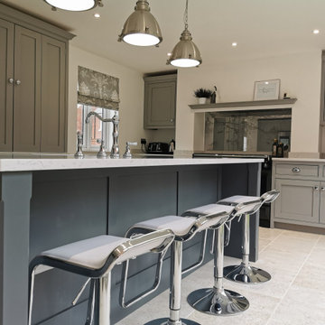 Dark grey hand painted kitchen with white worktops and chrome fixings