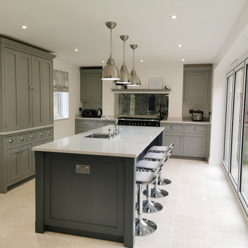Dark grey hand painted kitchen with white worktops and chrome fixings