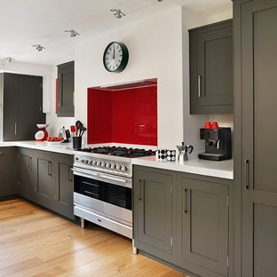 Inspiration for a traditional l-shaped kitchen in Devon with shaker cabinets, grey cabinets, red splashback, glass sheet splashback, stainless steel appliances, medium hardwood flooring and white worktops.