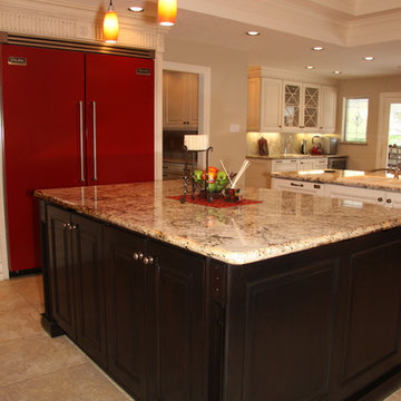Dark island anchors white kitchen with bright red appliances & carved moldings