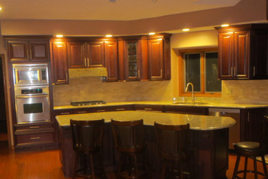 Inredning av ett modernt mellanstort kök, med en dubbel diskho, luckor med upphöjd panel, skåp i mörkt trä, granitbänkskiva, beige stänkskydd, stänkskydd i keramik, rostfria vitvaror, mörkt trägolv och en köksö