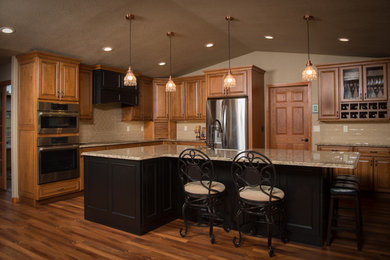 Large elegant l-shaped medium tone wood floor and brown floor eat-in kitchen photo in Other with a farmhouse sink, raised-panel cabinets, medium tone wood cabinets, granite countertops, beige backsplash, subway tile backsplash, stainless steel appliances and an island