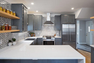 Medium sized traditional l-shaped kitchen/diner in Ottawa with a submerged sink, recessed-panel cabinets, blue cabinets, engineered stone countertops, grey splashback, stone tiled splashback, stainless steel appliances, light hardwood flooring and no island.