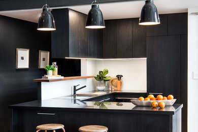 Cette image montre une cuisine design de taille moyenne avec un évier posé, une crédence en feuille de verre, un électroménager en acier inoxydable et un sol en bois brun.