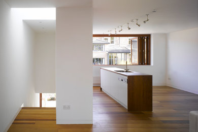 ダブリンにあるコンテンポラリースタイルのおしゃれなキッチン (白いキャビネット、木材カウンター、無垢フローリング) の写真