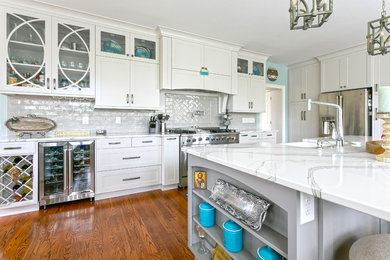 Kitchen photo in Charleston with white cabinets, gray backsplash and an island