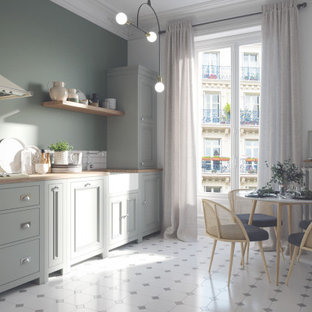 Design ideas for a mid-sized eclectic l-shaped eat-in kitchen in Paris with a farmhouse sink, flat-panel cabinets, green cabinets, wood benchtops, white splashback, ceramic splashback, ceramic floors, no island, grey floor and beige benchtop.