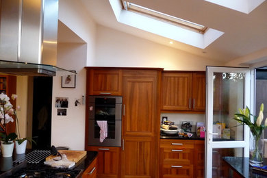 Photo of a medium sized contemporary u-shaped kitchen in Other with an island, recessed-panel cabinets, medium wood cabinets and granite worktops.