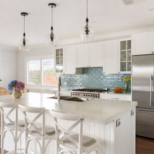 Design ideas for a transitional galley eat-in kitchen in Sydney with a double-bowl sink, shaker cabinets, white cabinets, blue splashback, subway tile splashback, stainless steel appliances, medium hardwood floors, with island, brown floor and white benchtop.