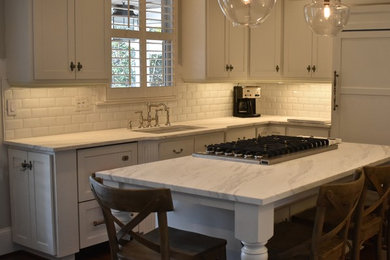 シャーロットにある高級な中くらいなトラディショナルスタイルのおしゃれなキッチン (アンダーカウンターシンク、落し込みパネル扉のキャビネット、白いキャビネット、大理石カウンター、白いキッチンパネル、サブウェイタイルのキッチンパネル、パネルと同色の調理設備、濃色無垢フローリング、茶色い床、白いキッチンカウンター) の写真