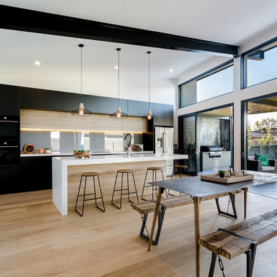 Example of a large trendy galley light wood floor and beige floor eat-in kitchen design in Adelaide with flat-panel cabinets, glass sheet backsplash, two islands, an undermount sink, black cabinets, gray backsplash and white countertops