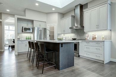 Kitchen pantry - mid-sized transitional l-shaped medium tone wood floor kitchen pantry idea in Calgary with a single-bowl sink, shaker cabinets, white cabinets, quartz countertops, gray backsplash, glass tile backsplash, stainless steel appliances and an island