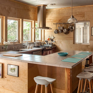 Idee per una cucina industriale di medie dimensioni con ante in legno chiaro, top piastrellato, elettrodomestici in acciaio inossidabile, pavimento in cemento, penisola, lavello da incasso, paraspruzzi beige e paraspruzzi in gres porcellanato