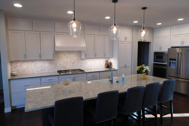 Example of an arts and crafts l-shaped medium tone wood floor eat-in kitchen design in Other with a farmhouse sink, flat-panel cabinets, white cabinets, quartz countertops, white backsplash, glass tile backsplash, stainless steel appliances and an island