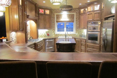 Exempel på ett klassiskt u-kök, med en rustik diskho, luckor med infälld panel, skåp i ljust trä, beige stänkskydd, stänkskydd i glaskakel, rostfria vitvaror och en köksö