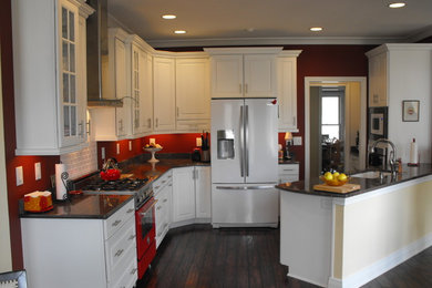 Exempel på ett mellanstort klassiskt l-kök, med en undermonterad diskho, luckor med upphöjd panel, vita skåp, granitbänkskiva, vitt stänkskydd, stänkskydd i keramik, vita vitvaror, mörkt trägolv och en halv köksö