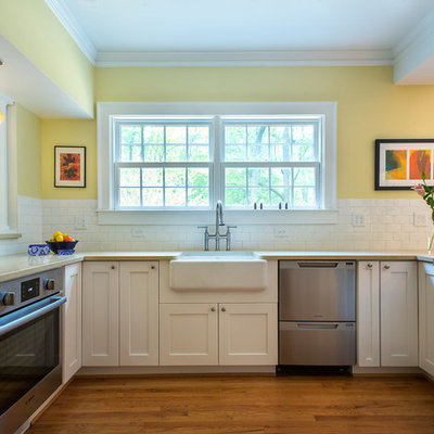 Open concept kitchen - mid-sized traditional u-shaped medium tone wood floor and brown floor open concept kitchen idea in Atlanta with a farmhouse sink, shaker cabinets, white cabinets, white backsplash, subway tile backsplash, stainless steel appliances and a peninsula