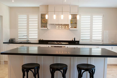 シドニーにある高級なトラディショナルスタイルのおしゃれなキッチン (アンダーカウンターシンク、シェーカースタイル扉のキャビネット、御影石カウンター、ベージュキッチンパネル、セラミックタイルのキッチンパネル、シルバーの調理設備、トラバーチンの床) の写真