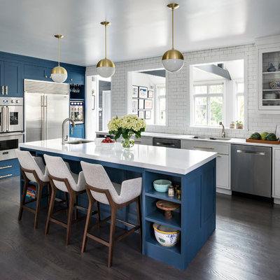 Kitchen - large transitional l-shaped brown floor and dark wood floor kitchen idea in New York with a double-bowl sink, shaker cabinets, blue cabinets, quartz countertops, white backsplash, stainless steel appliances, an island and subway tile backsplash