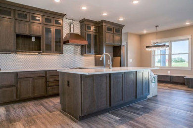 Cottage l-shaped medium tone wood floor open concept kitchen photo in Columbus with an undermount sink, shaker cabinets, medium tone wood cabinets, quartz countertops, white backsplash, porcelain backsplash, stainless steel appliances, an island and white countertops